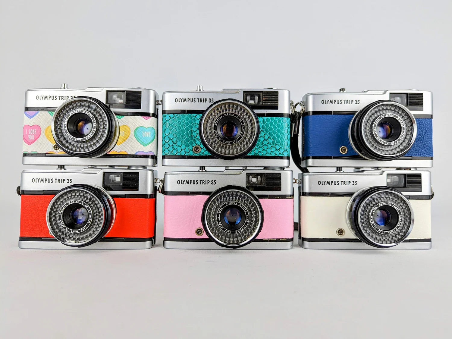 Multiple Olympus Trip 35 cameras in different colours stacked together