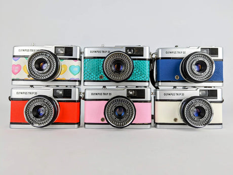 Multiple Olympus Trip 35 cameras in different colours stacked together
