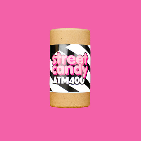 Cylindrical container with 'street candy ATM400' label on a wooden surface and gray background