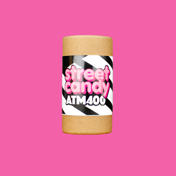 Cylindrical container with 'street candy ATM400' label on a wooden surface and gray background