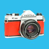 Pentax K1000 Red Leather Vintage SLR 35mm Film Camera with Pentax f/2 50mm Prime Lens.