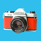 Pentax K1000 Red Leather Vintage SLR 35mm Film Camera with Pentax f/2 50mm Prime Lens.